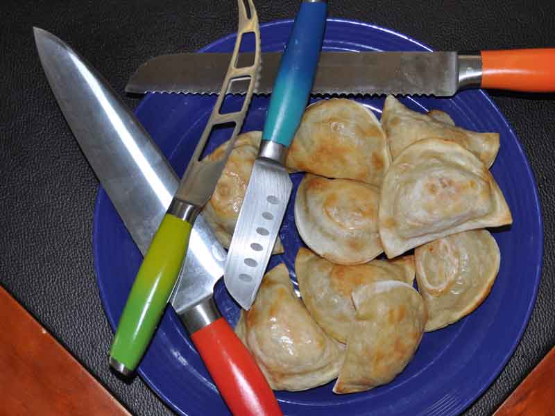 Pierogies and knives on a blue plate